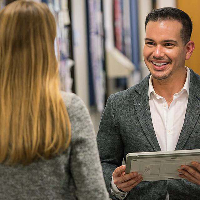 Dr. Rivera Pérez listening during a conversation while holding a tablet